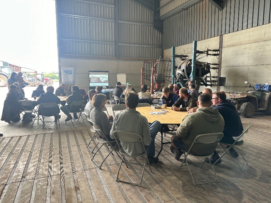 Farmers sat round tables listening to a talk at a Monitor Farm meeting in a grain shed
